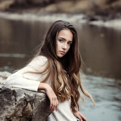 Teen girl leaning on rock by river