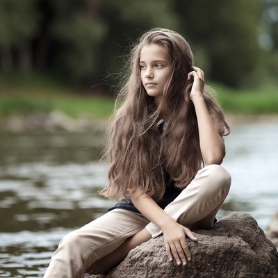 Girl sitting on rock by river