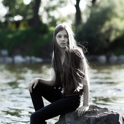 Girl sitting on rock by river