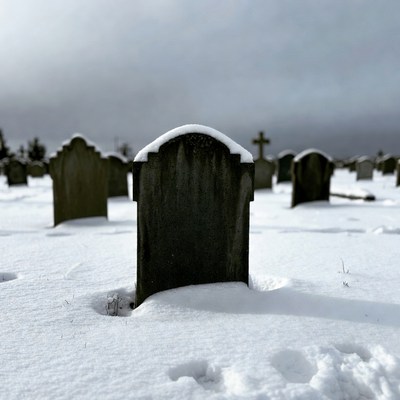 Snowy gravestones in foggy cemetery