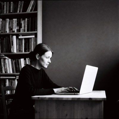 Woman working on laptop by bookshelves