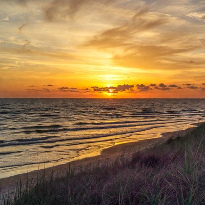 Sunset over ocean beach with dunes