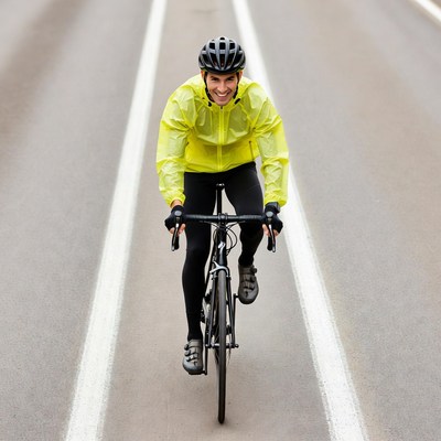 Man cycling on road in yellow jacket