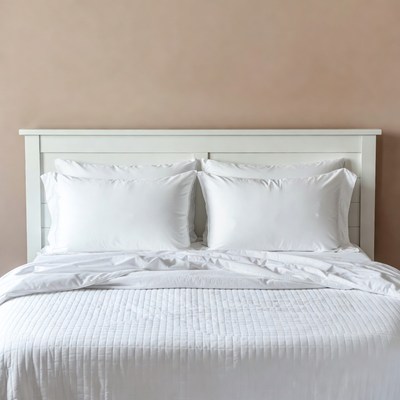 White Bed with Pillows on Beige Wall