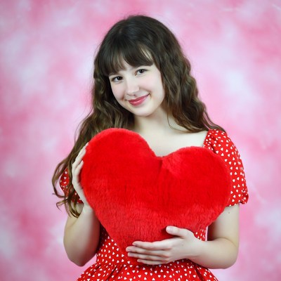 Girl hugging large red heart pillow