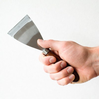Man's hand holding putty knife