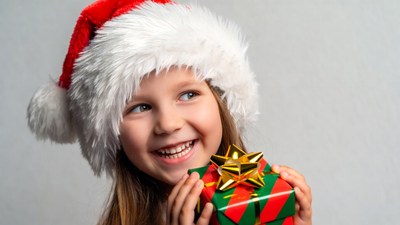 Girl holding Christmas gift in Santa hat
