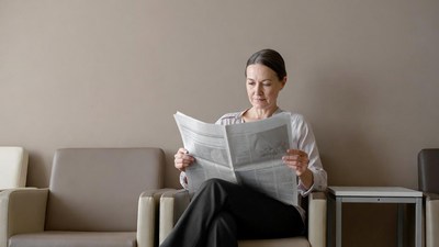 Woman reading newspaper in waiting room