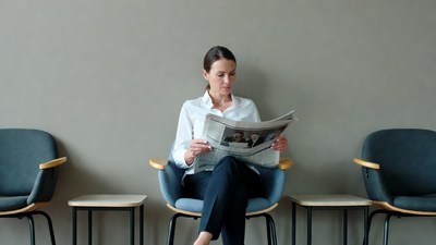 Woman reading newspaper in waiting room