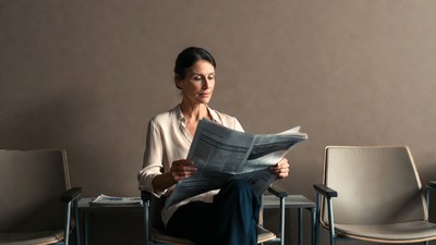Woman reading newspaper in waiting room