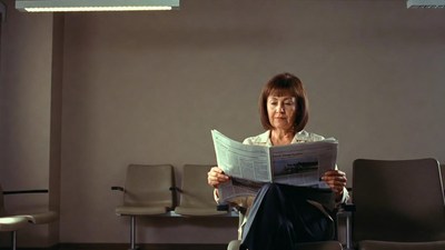 Woman reading newspaper in waiting room