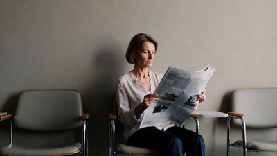 Woman reading newspaper in waiting room