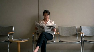 Woman reading newspaper in waiting room