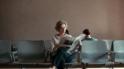 Woman reading newspaper in waiting room