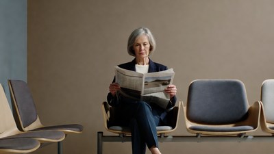 Elderly woman reading newspaper in waiting room