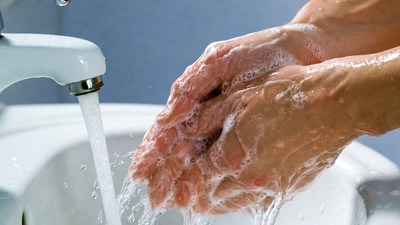 Hands washing under faucet with soap