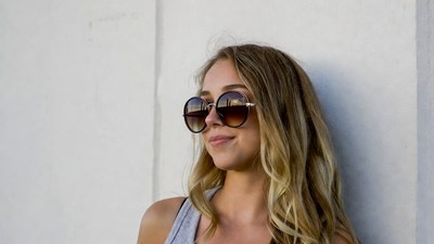 Blonde woman in sunglasses against wall