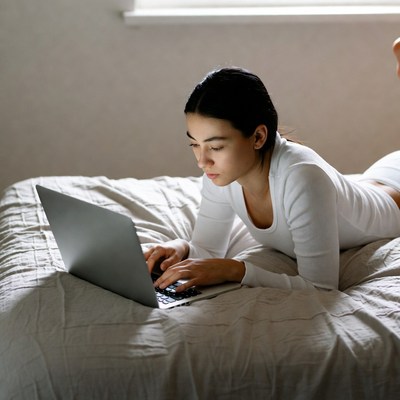 Asian woman using laptop on bed