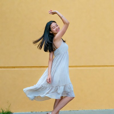 Asian woman dancing against yellow wall