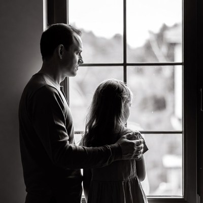Father embracing daughter at window