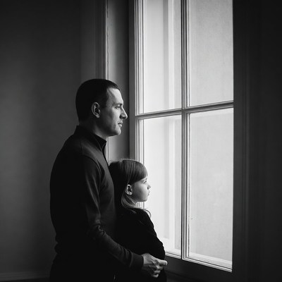 Father and daughter looking out window
