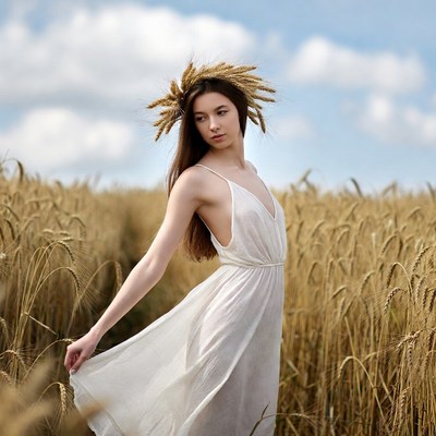 Woman in wheat crown and dress in field