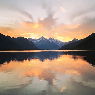 Sunset over snowy mountains and lake