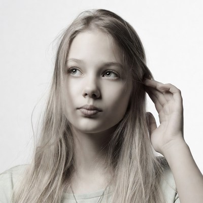 Blonde girl touching ear thoughtfully