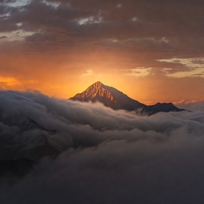 Mountain peak above clouds at sunset