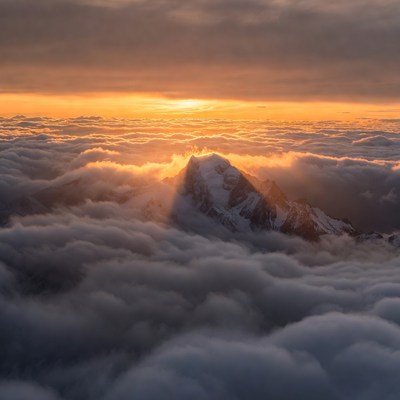 Snowy Mountain Peak Above Clouds at Sunset