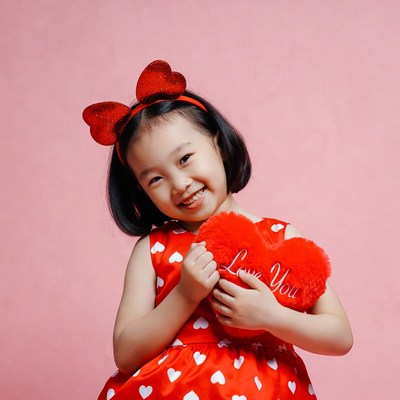 Asian girl holding red heart plush