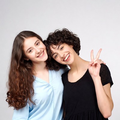 Two smiling girls making peace sign