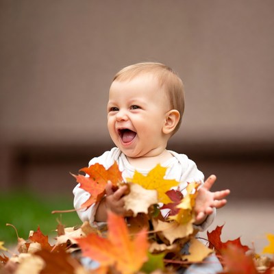 Baby laughing with autumn leaves