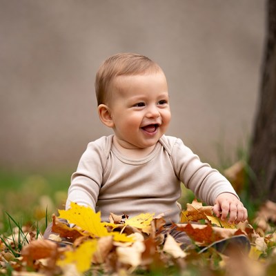 Baby boy laughing in autumn leaves
