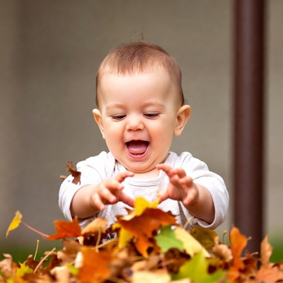 Baby laughing with autumn leaves