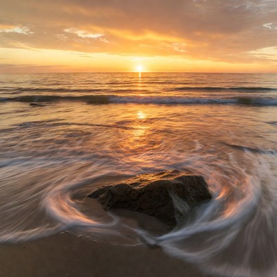 Sunset Swirling Waves Around Beach Rock