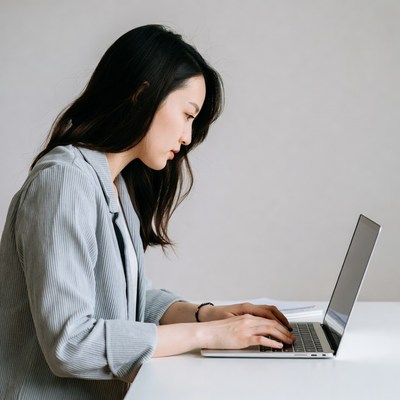 Asian woman typing on laptop