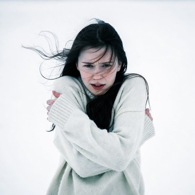 Woman shivering in snowy wind