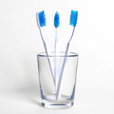 Three Blue Toothbrushes in Glass