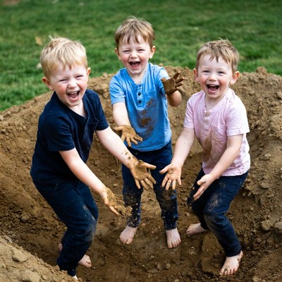 Three boys playing in mud pit