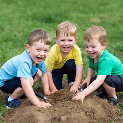 Three boys digging in grass