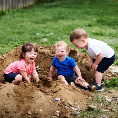 Toddlers playing in backyard sand pile