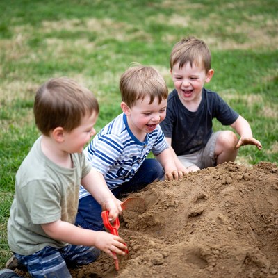 Boys playing with shovel in sand pile