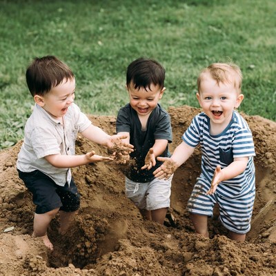Three boys playing in dirt pile