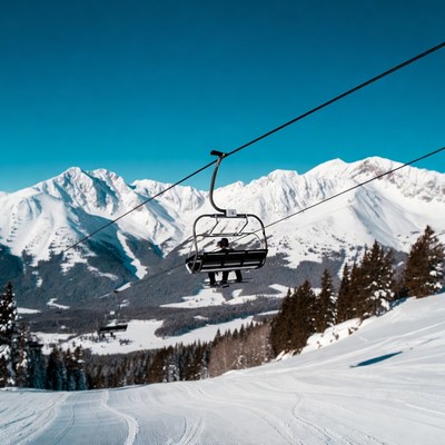Skier on chairlift over snowy mountains