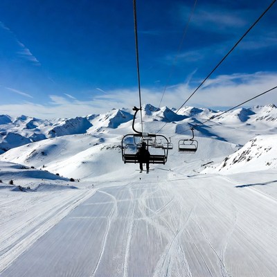 Skier on chairlift over snowy mountains
