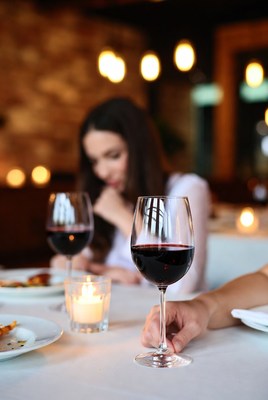 Woman holding wine glass at candlelit dinner