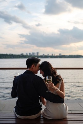 Asian couple toasting wine at sunset dock