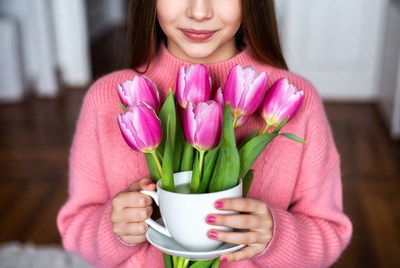 Girl holding pink tulips in white cup