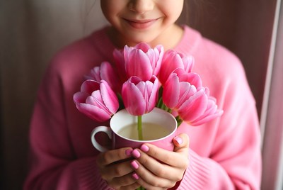 Girl holding pink tulips and teacup